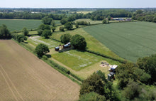 Aerial view of a rural landscape with fields and trees under a clear sky.